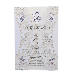 Laser cut white wedding invitation card with intricate floral patterns and heart cutout