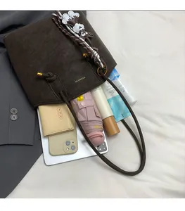 Detail showing high-capacity dark brown suede tote with accessories and lifestyle items