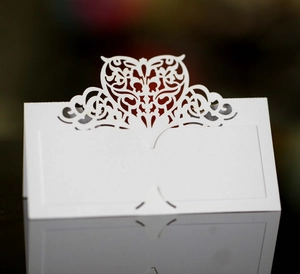 Detail of laser-cut heart patterns on white pearlescent paper wedding place cards