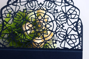 Intricate laser-cut geometric floral pattern on navy blue wedding invitation card detail
