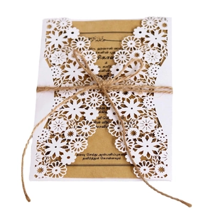 Macro detail of laser-cut white lace wedding invitation with kraft paper and hemp rope