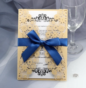Détail d'invitation dorée découpée au laser avec ruban bleu marine et carte blanche