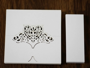 Detail of laser-cut heart pattern on white pearlescent paper wedding place cards