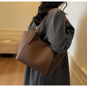 Side view of dark brown pebbled leather tote bag worn by a model in minimalist interior