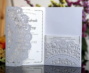 Close-up of laser-cut lace pattern on elegant white wedding invitation card set