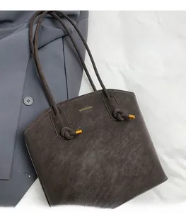 Detail of grey bucket bag with MANXIANG logo and elegant knotted rope shoulder straps