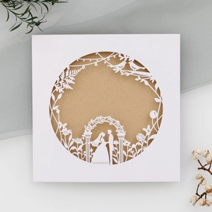 Detailed laser-cut wedding invitation featuring a floral gate and couple silhouette
