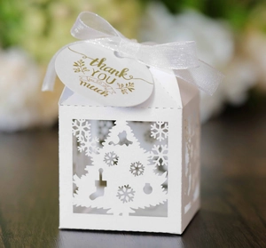 Detail of white laser-cut Christmas candy box with tree patterns and thank you tag