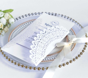 Détail de l'invitation de mariage découpée au laser avec ruban blanc sur plat décoré