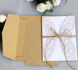Close-up of laser-cut floral wedding invitation with kraft paper and rustic twine