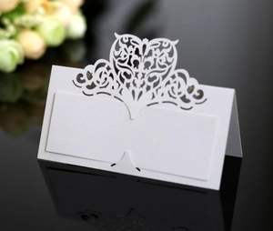 Macro view of white laser-cut heart seat card on a reflective surface for weddings