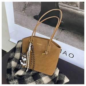 Detail of a brown suede tote bag with golden lettering and a cute puppy keychain