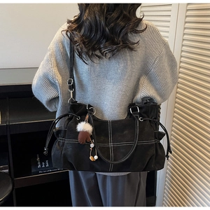Detail of large black tote bag with white contrast stitching and a glove charm