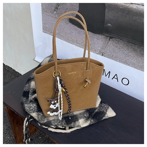 Close-up of tan suede tote bag featuring woven rope detail and a cute dog pendant