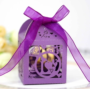 Detail of laser-cut purple paper candy box with diamond heart patterns and silk ribbon bow