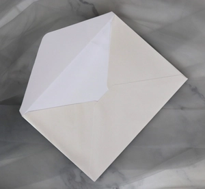 Detailed top view of a premium white textured paper envelope on grey marble background