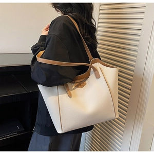 Detail of white lychee leather tote bag featuring brown trim and dual shoulder straps