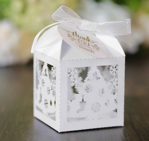 Detail of white laser-cut Christmas candy box with snowflake tree patterns and ribbon