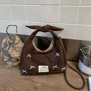 Detail of vintage brown suede dumpling bag with bow handles and pearl accents