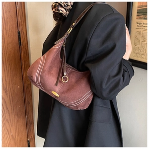 Detail of retro brown suede hobo bag with white stitching on a black blazer