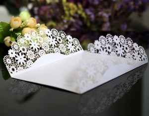 Macro shot of white laser-cut floral invitation cover with intricate lace detailing