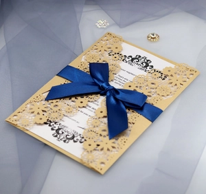 Détail du motif floral découpé au laser sur invitation de mariage dorée avec ruban