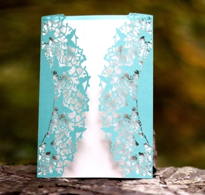 Macro view of laser-cut light blue wedding invitation with butterfly and flower patterns
