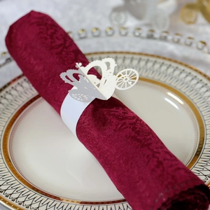 Macro detail of laser-cut white pumpkin carriage napkin ring on a deep red napkin