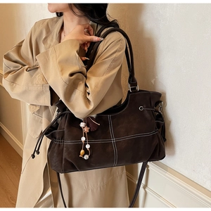 Close-up of brown suede tote bag with contrast white stitching and beaded star pendant