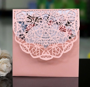 Detail of pink laser cut lace wedding invitation with intricate mandala flower patterns