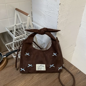 Close-up of brown suede hobo bag featuring blue bows and a decorative fabric patch