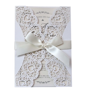 Laser-cut white heart wedding invitation set with cream inner card and satin ribbon bow