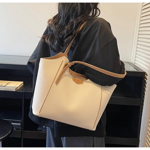 Detail of large beige tote bag with brown straps and textured litchi grain leather
