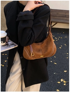 Detail view of brown suede shoulder bag with contrast stitching and gold metal ring