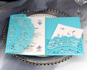 Detail of laser cut lace wedding invitation on glass tray with elegant silk background