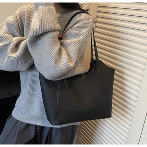Side view of large black pebble leather tote bag with elegant metallic shield logo