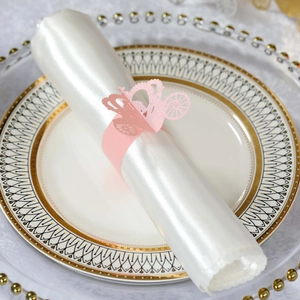 Detail of pink laser-cut carriage napkin ring on white silk cloth for wedding table decor