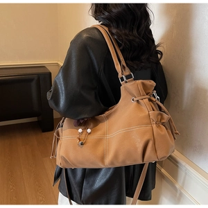 Detail of brown faux leather tote bag with white contrast stitching and side drawstring