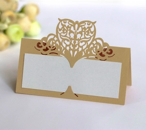 Close-up of laser-cut heart pattern on gold place cards with elegant pearl white inserts