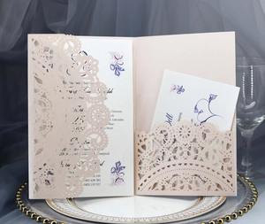 Close-up of laser-cut lace wedding invitation with floral card on elegant silver plate