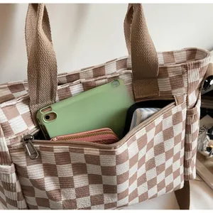 Detail of corduroy tote bag with brown checkerboard pattern and spacious front zipper pocket