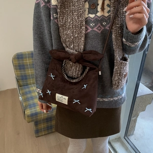 Detail of vintage brown suede dumpling bag with bow strap and cat patch decor