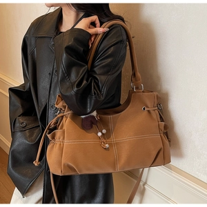 Close-up of brown tote bag featuring white contrast stitching and side drawstring detail