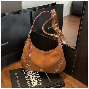 Detail of vintage brown suede hobo bag with contrast stitching and golden hardware