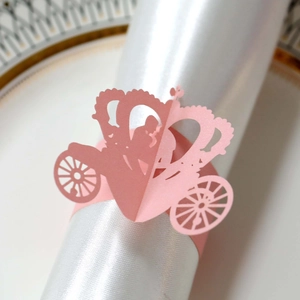 Macro detail of laser-cut pink paper napkin ring in carriage shape on white satin