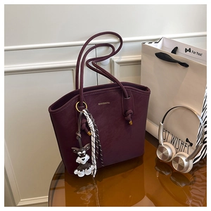 Detail of burgundy leather tote bag with schnauzer charm and striped silk scarf decor