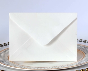 Close-up of a premium white paper envelope with a classic triangular flap on a decorative tray