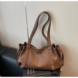 Détail du sac cabas en cuir marron motif litchi avec cordon et boucle de réglage métal