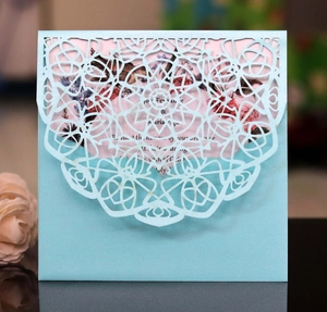 Close-up of laser-cut wedding invitation with intricate hollow patterns in ice blue pearl paper