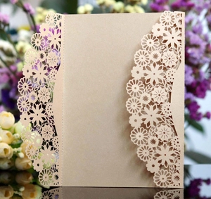 Macro detail of laser-cut champagne gold floral invitation with pearlescent finish
